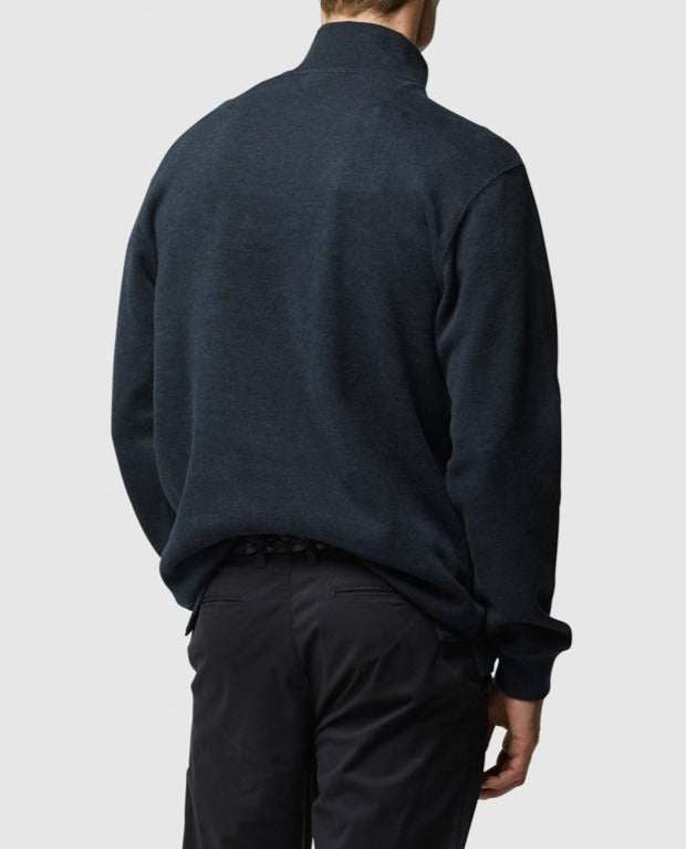 A person stands with their back to the camera, wearing a dark Rodd & Gunn Alton Ave Sweat and black pants. Their left hand rests in their pocket against a plain, light gray backdrop.