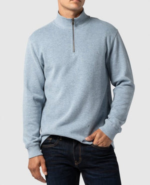 Wearing the Rodd & Gunn Alton Ave Sweat, a light blue 100% cotton quarter-zip sweater, and dark jeans, a person stands against a plain background with one hand in their pocket.