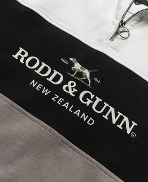 Close-up of a Rodd & Gunn Hillop Sweat. The black section prominently displays the brand name "RODD & GUNN" in white, with a hunting dog logo and the text "REGO 1946." This stylish sweatshirt, made from 100% cotton, features a zipper at the top.