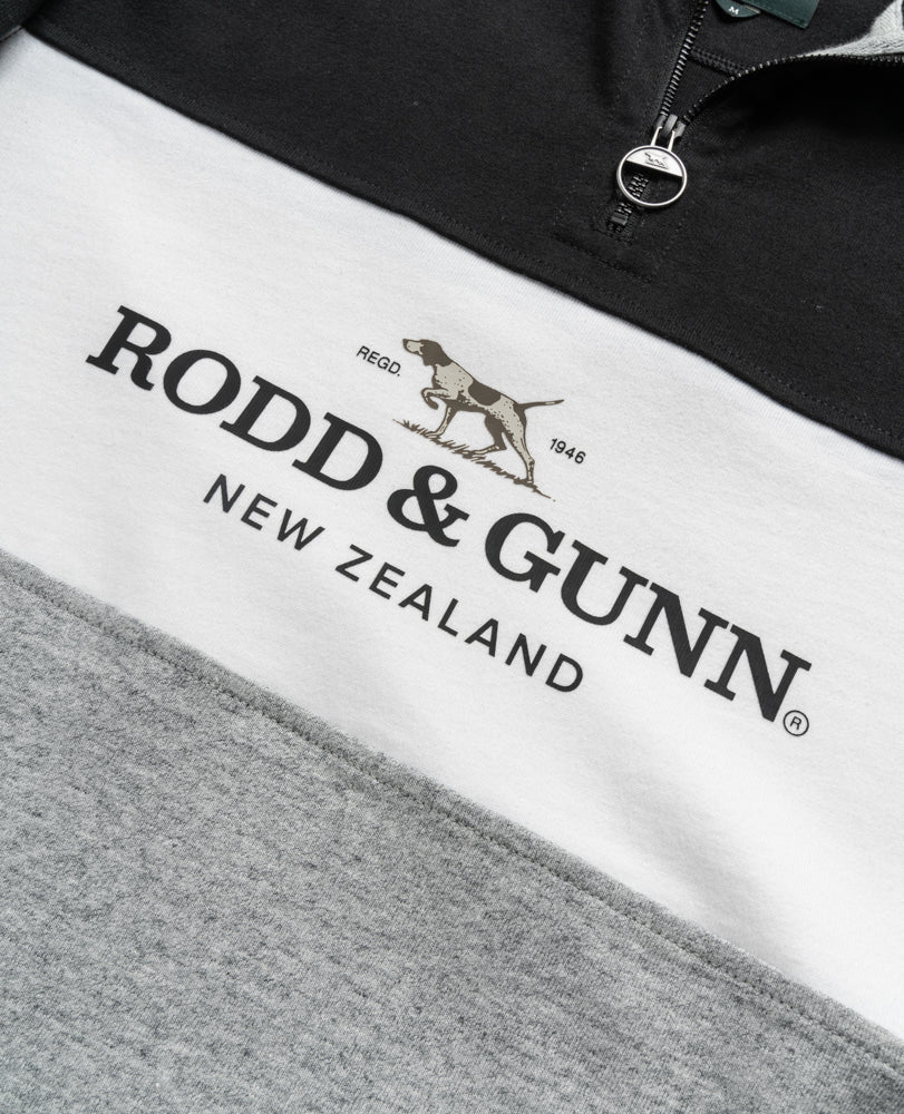 This close-up of a Rodd & Gunn Hillop Sweat highlights its color block design in black, white, and gray. Made from 100% cotton, it features a logo with a pointing dog and the text "RODD & GUNN NEW ZEALAND.
