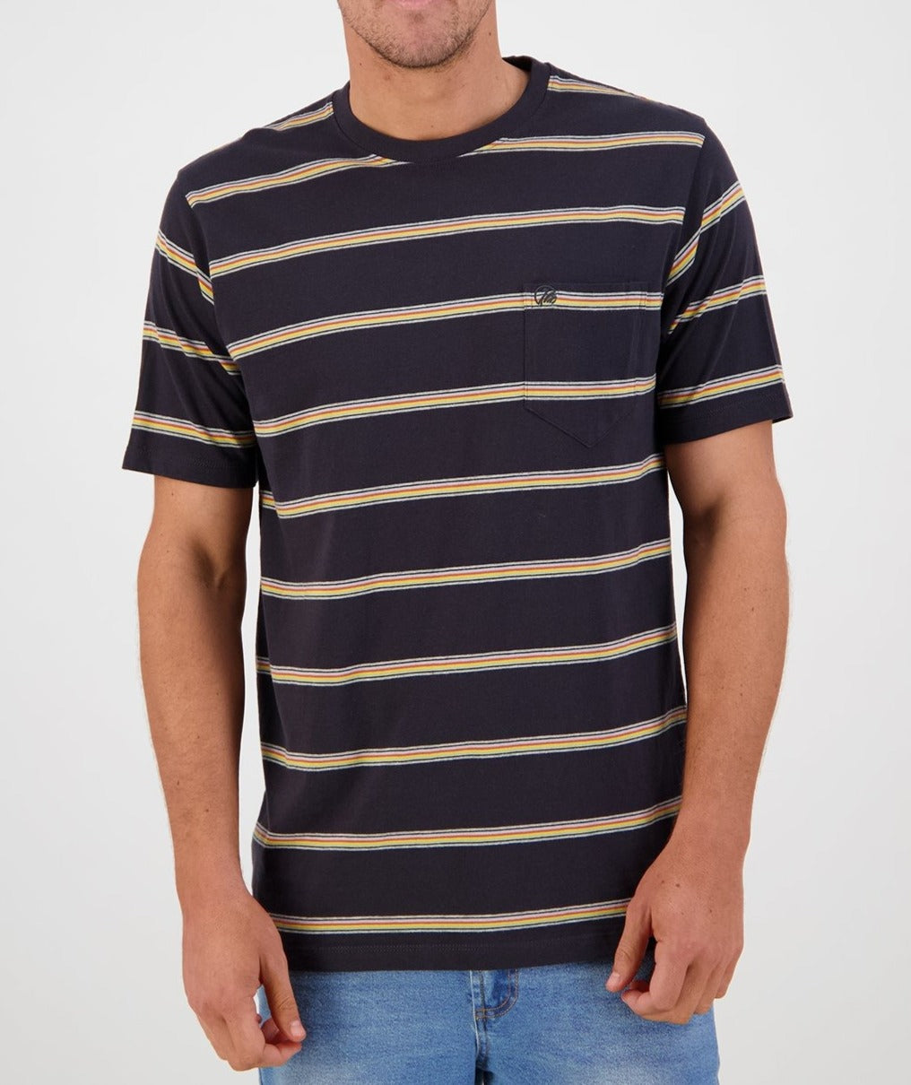 A person is standing in front of a plain light background, wearing the Swanndri Dome Valley Stripe Tee—a comfortable and casual, dark blue t-shirt made of 100% cotton. It features horizontal yellow and gray stripes along with a small square chest pocket on the left side adorned by the subtle Swanndri logo. The individual is also dressed in blue jeans.
