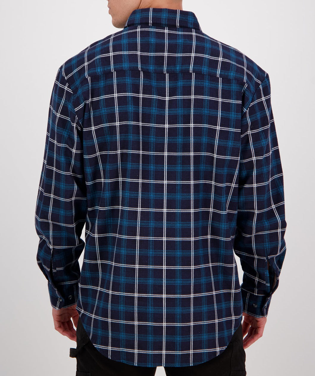 A person wearing a navy blue and white plaid long sleeve shirt from the Swanndri Egmont Flannelette Twin Pack is seen from the back. They have dark pants on, and the background is plain white.