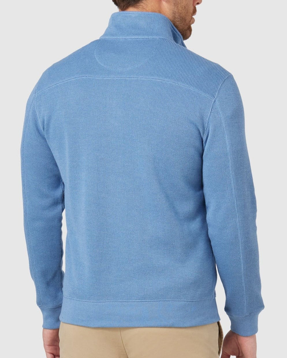 A person wearing the Blazer Heather Half Zip Sweat in light blue, paired with beige pants, stands back to the camera. The ribbed texture complements the outfit's casual vibe against a plain white background.