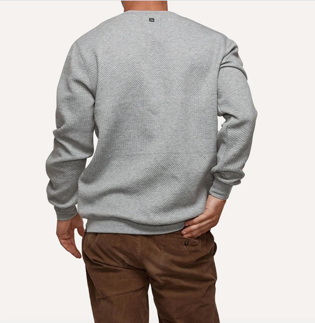 A person standing with their back to the camera, wearing the comfortable Industrie The Robinson Crew jumper in light gray and brown pants. The person has their left hand in their back pocket. The background is plain white.