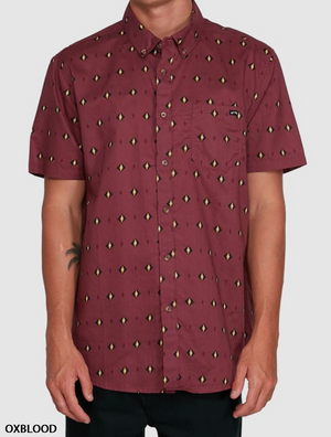 A person in a Billabong Sundays Mini Shirt—oxblood, short sleeves, button-up, diamond pattern, chest pocket, 100% cotton—stands against a plain light background.