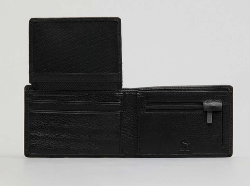 The Rusty Busted Leather Wallet, in black leather, is open to reveal card slots on the left, a zippered coin pocket on the right, and an extra flap with more slots. It is elegantly displayed on a plain light surface.