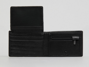 The Rusty Busted Leather Wallet, in black leather, is open to reveal card slots on the left, a zippered coin pocket on the right, and an extra flap with more slots. It is elegantly displayed on a plain light surface.