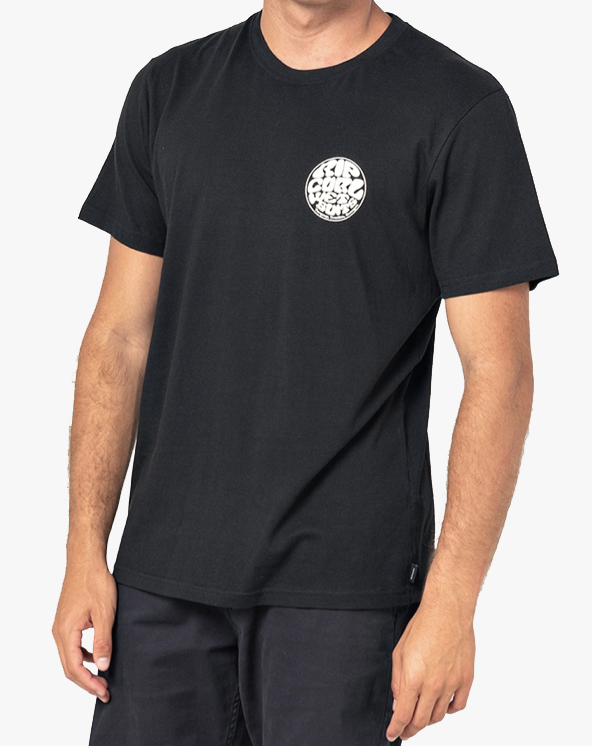 A person wearing the Rip Curl Wetsuit Icon Tee, featuring a plain black design with a small Rip Curl print on the left chest, is standing against a light background. The individual has light skin, and their right arm is partially visible along their side.
