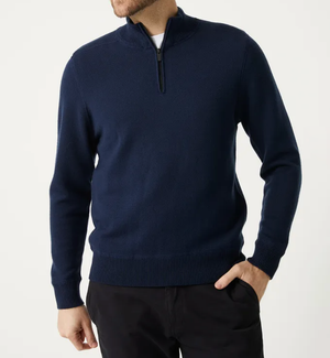 A man wearing the Toorallie Grafton Half Zip Knit in navy blue with black pants stands against a plain light background, one hand in his pocket and his face partially out of frame.