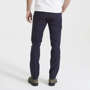 A person is shown from the back, wearing a white shirt and dark blue Levis Workwear 505 Utility Pant with durable oversized pockets, paired with beige and brown boots. The background is plain white.