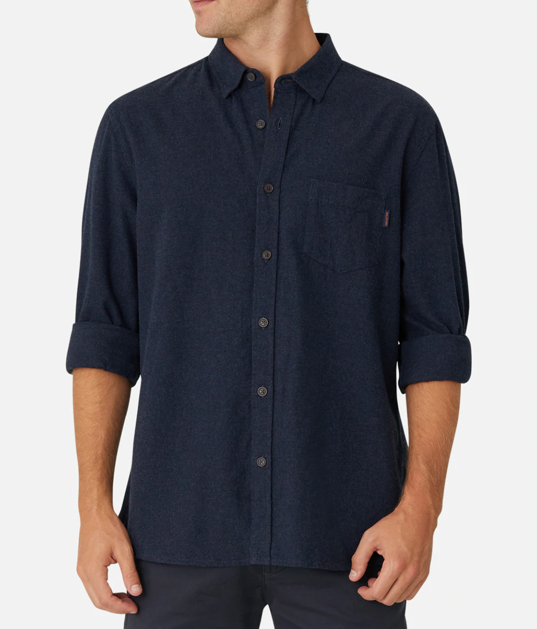 A person wearing Industrie The Taylor Shirt in dark blue with long sleeves rolled up to the elbows. The comfortable and casual shirt features a chest pocket on the left side, and the person is standing against a plain white background. The face and background details are not visible.