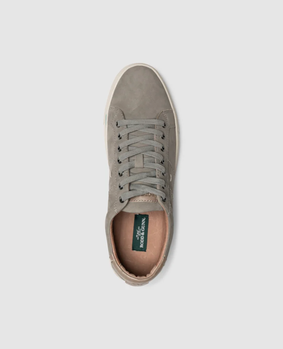 The Rodd & Gunn Endeavour Spirit Sneaker, a single gray nubuck leather shoe with a white rubber sole and gray laces, showcases a green insole inscribed with "RODD & GUNN" in white for added comfort. The sneaker is presented from a top-down perspective against a white background.