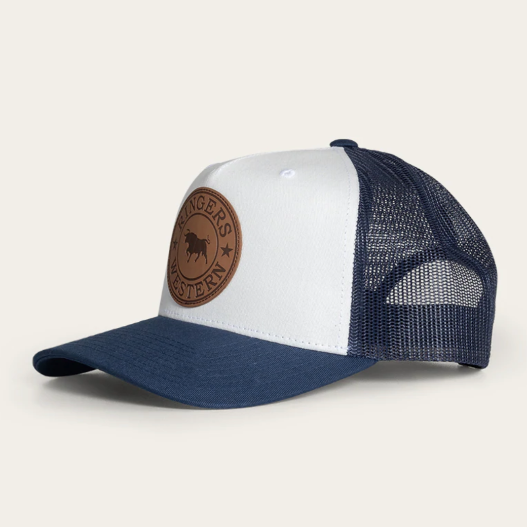 The Ringers Western Whitby Trucker Cap features a white front panel with a brown leather patch displaying a buffalo and stars, a curved brim, and blue mesh back panels for classic appeal.