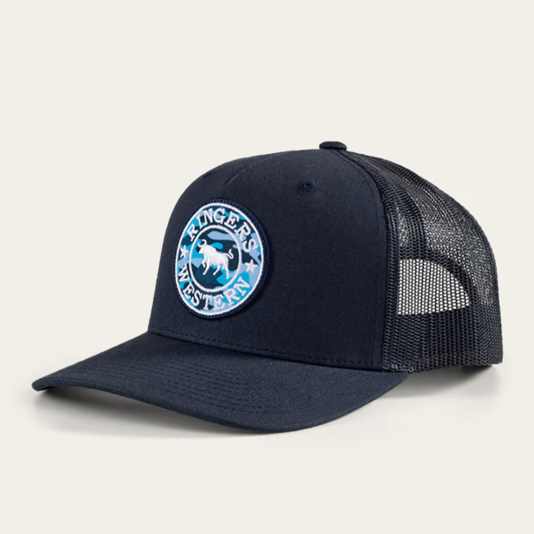 The Ringers Western Chase Trucker Cap is a dark blue hat featuring a mesh back, adjustable strap, and a round logo with a cattle image and "Ringers Western" text.