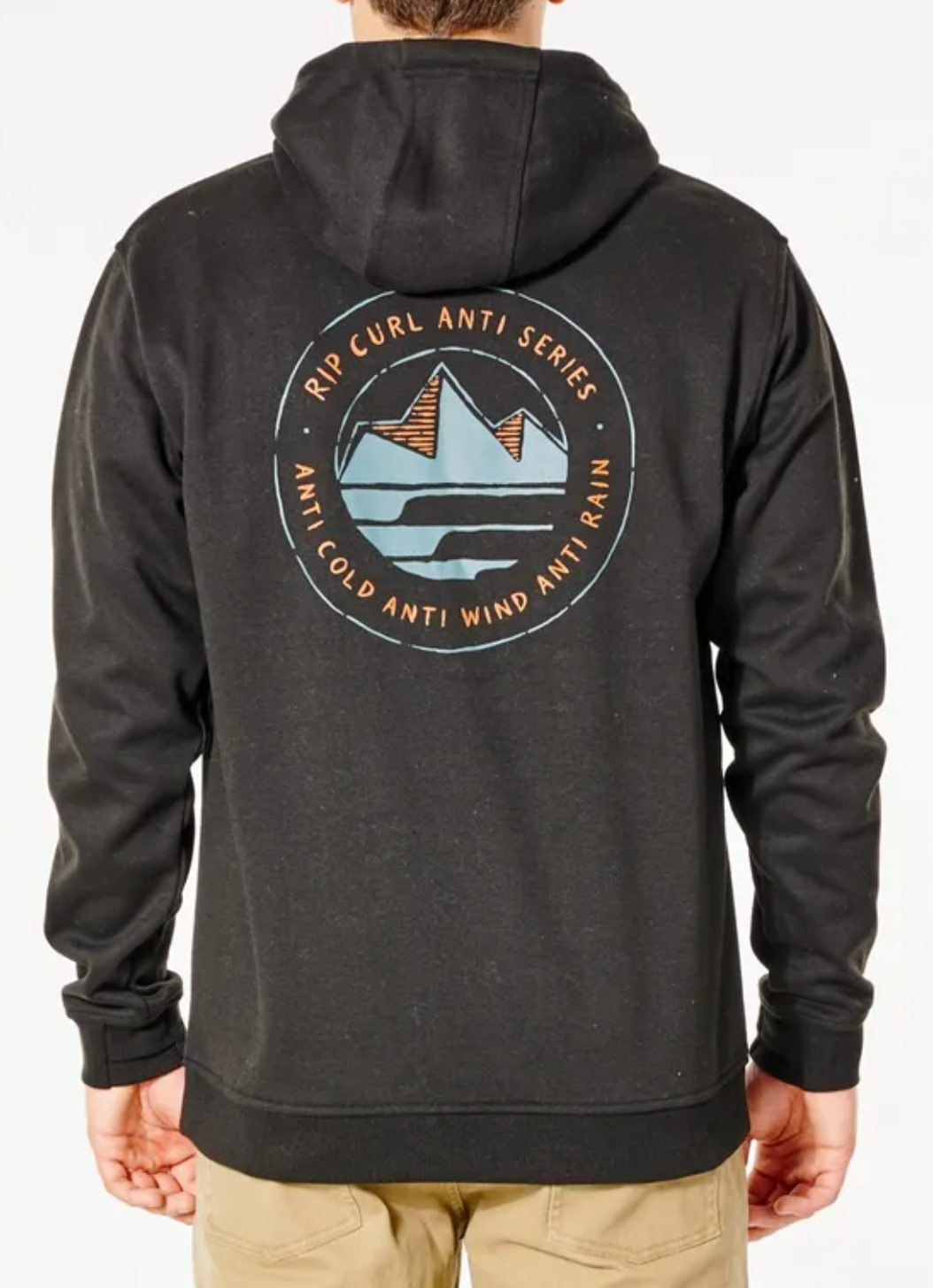A person wearing the Rip Curl Anti Series Journey Hood, a black jacket with a circular mountain logo on the back. The text reads "Rip Curl Anti Series" and "Anti Cold, Anti Wind, Anti Rain." They stand facing away, hands in pockets.