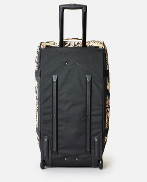 The Rip Curl Jupiter 80L Sunday Swell Travel Bag is a black suitcase with floral-patterned sides, crafted from recycled polyester. It features a retractable handle and sturdy wheels, standing upright against a plain white background.