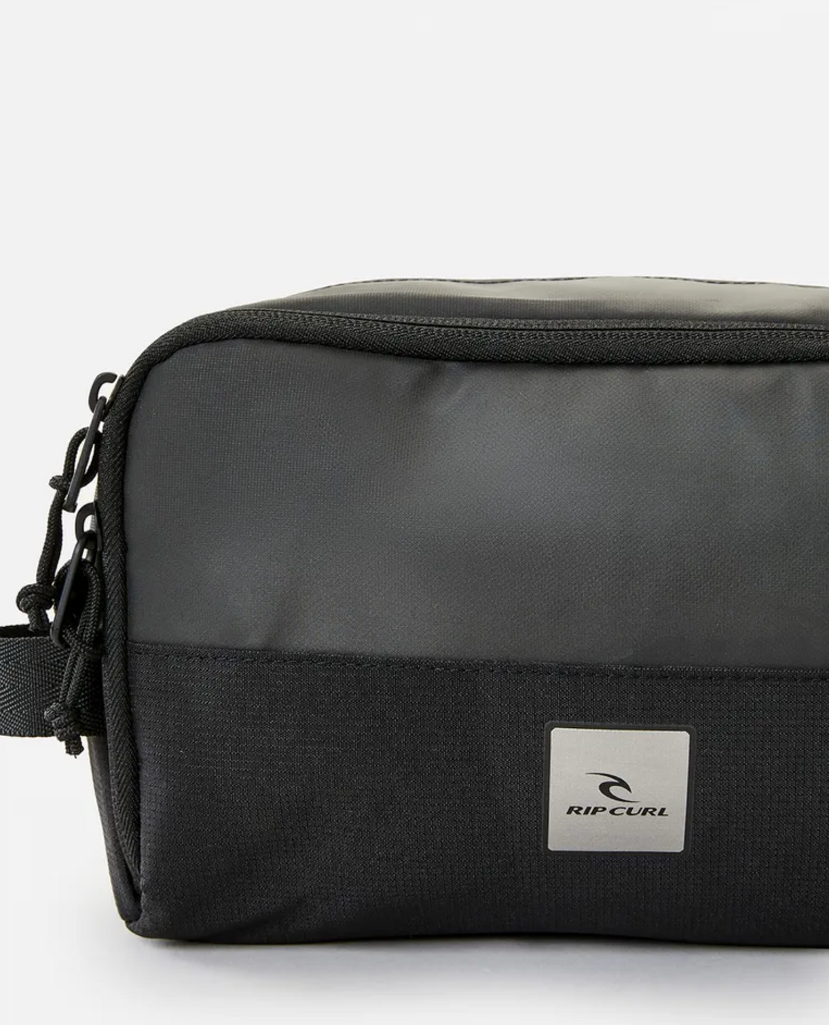 A Rip Curl Groom Toiletry Midnight bag crafted from durable polyester in black, showcasing a rectangular shape, zip closure, and a small white logo patch on the front. The bag is placed against a plain white background.
