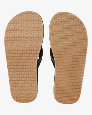 The image displays the underside of a pair of Billabong All Day Impact Thongs, featuring light brown soles with a textured pattern for enhanced grip. The Vegan Nubuck upper part, which is black in color, is partially noticeable. These thongs are equipped with a comfort footbed and are placed side by side for showcase.