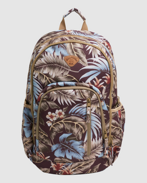 The Billabong Slow Daze Roadie Backpack showcases a tropical floral pattern in blue, brown, and cream hues. Crafted from recycled polyester, it boasts multiple zippered compartments, a leather patch on the front, a top handle, and adjustable shoulder straps.