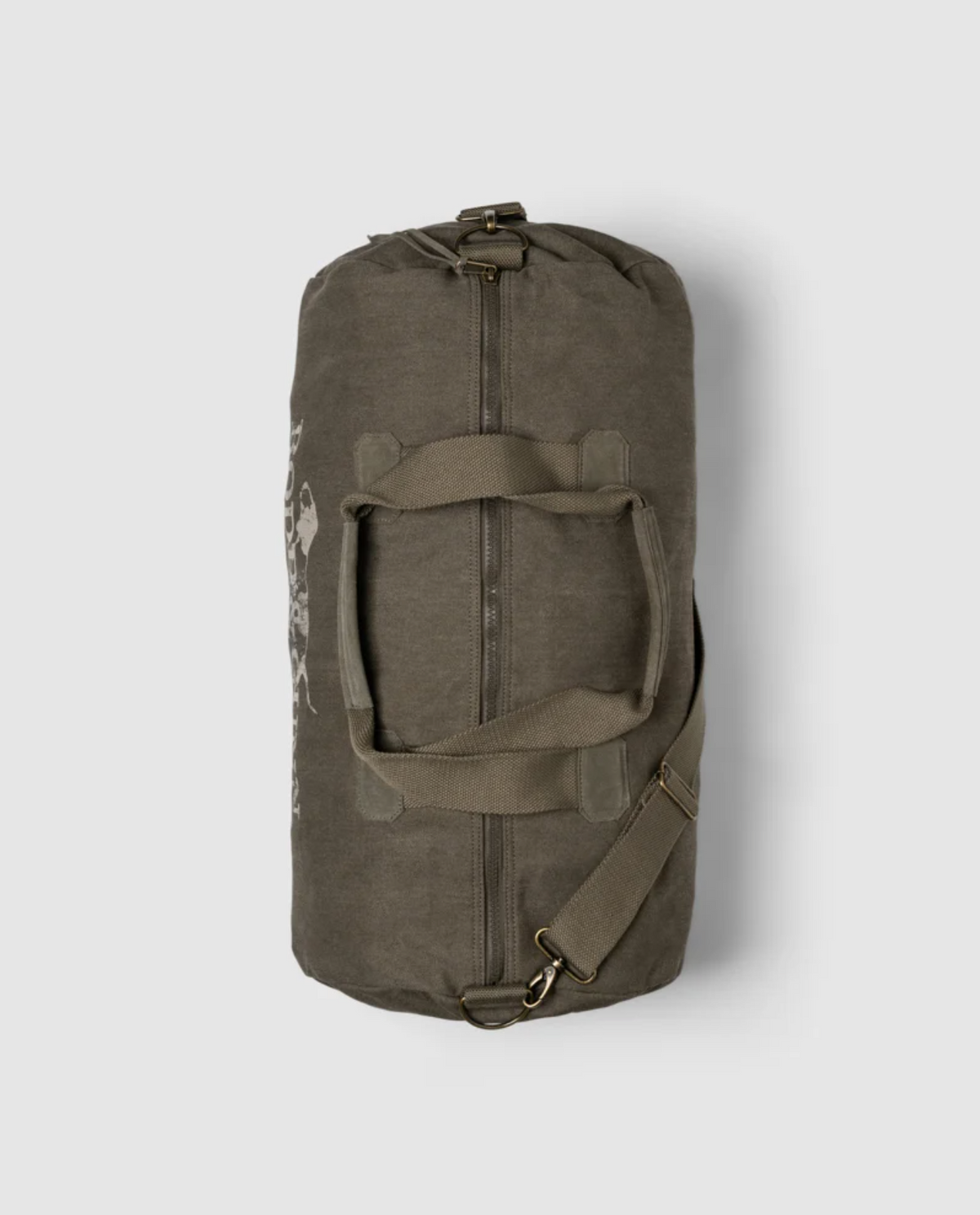 The Rodd & Gunn Double Barrel Duffle Bag features a top-view greenish-brown cotton canvas with sturdy handles, an adjustable shoulder strap, and a slightly worn texture. It has a subtle pattern on one side against a plain light gray background.