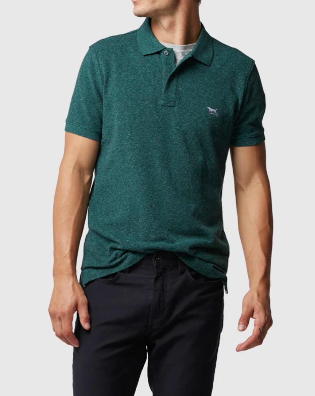 A person in a green Rodd & Gunn The Gunn Polo, made from premium Australian cotton, stands with arms bent slightly. The small chest logo complements the modern fit, matched with dark pants against a light gray background.