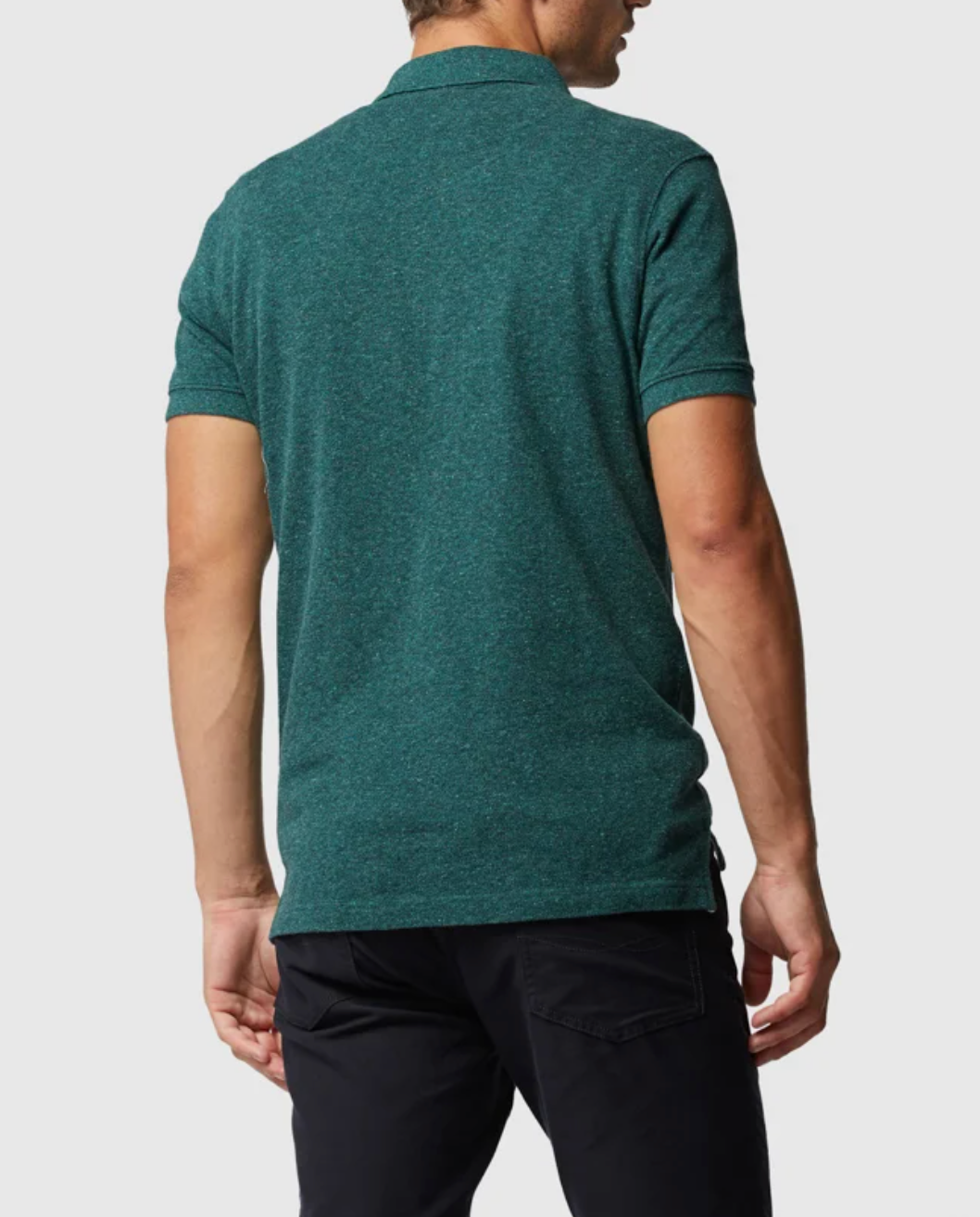A man in a modern fit Rodd & Gunn The Gunn Polo in teal and black pants stands with his back to the camera against a plain background.