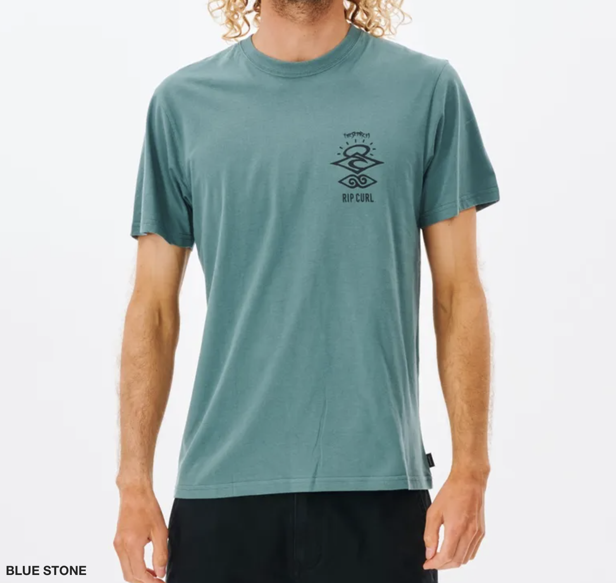 Wearing the Rip Curl Search Icon Tee, a short-sleeved casual shirt in blue stone made of organic cotton with a small graphic and "Rip Curl" on the left chest, the outfit pairs effortlessly with black pants against a plain white background.