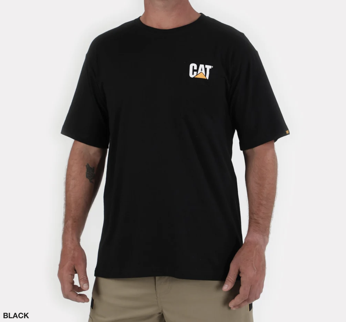 A person wearing a comfortable CAT Trademark Tee, which is black and features a small white and yellow CAT logo on the left chest. The individual has short sleeves and is also dressed in khaki pants, ideal for job site safety. The background is white.