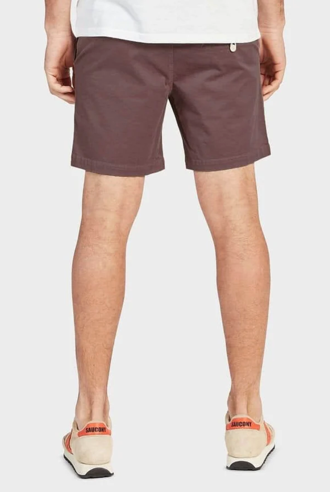 Rear view of a person wearing Academy Brand Volley Shorts in casual brown with an elastic waist, paired with white sneakers featuring red accents, standing against a plain background.