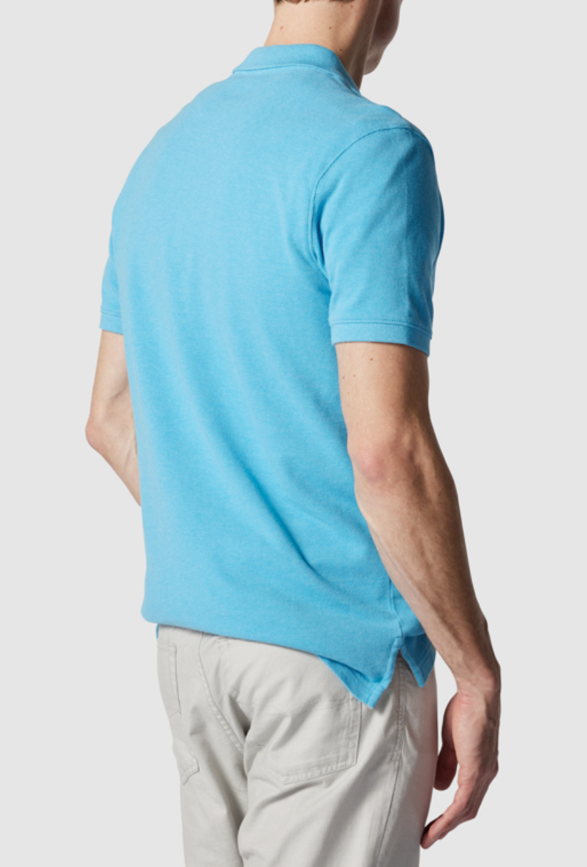 A person in a modern fit light blue Rodd & Gunn The Gunn Polo, made from Australian Cotton, and beige pants stands with their back to the camera. Their short sleeves show their right arm resting at their side against a plain white backdrop.