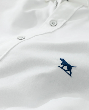 Close-up of a Rodd & Gunn Gunn Oxford Sports Fit Shirt, crafted from 100% cotton, featuring a small blue embroidered animal logo on a surfboard and white buttons along the placket.