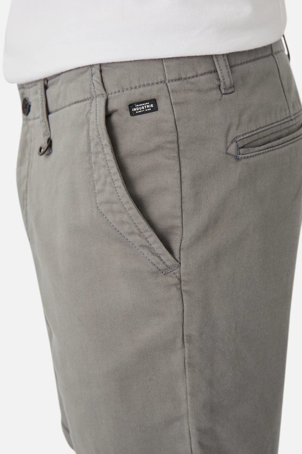 A close-up showcases a person wearing Industrie The Rinse Drifter Short, light gray cotton shorts paired with a white top. The relaxed fit features front pockets and a small sewn label near the waist, beautifully capturing the front side and upper section.