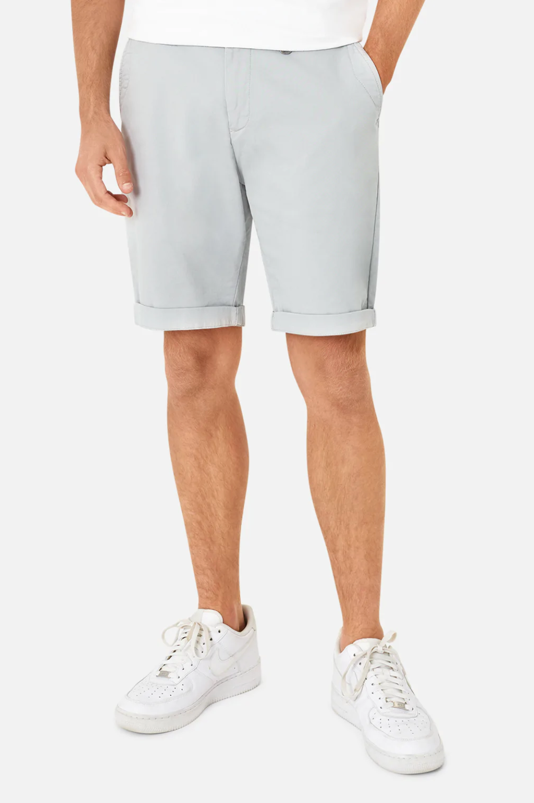 A person in Industrie The Rinse Drifter Shorts, light gray with rolled cuffs, pairs them with white sneakers and a glimpse of a white shirt against a plain white backdrop. Made from comfortable cotton, this relaxed fit creates a stylish appearance.