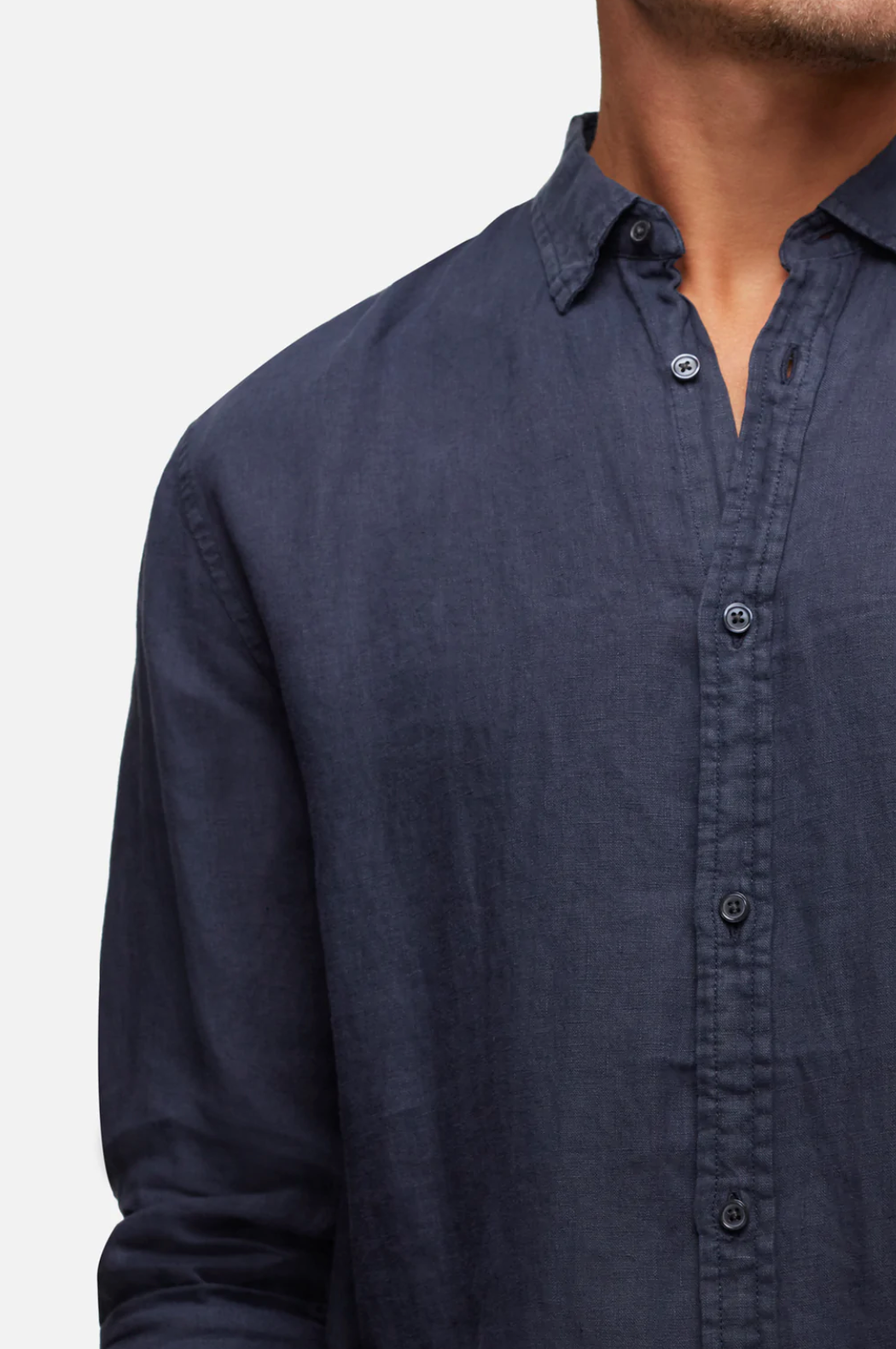 A person is shown from the shoulders to the waist against a plain background wearing a navy blue, relaxed fit, long-sleeve shirt made of 100% linen, known as the Industrie The Tennyson Linen Shirt.