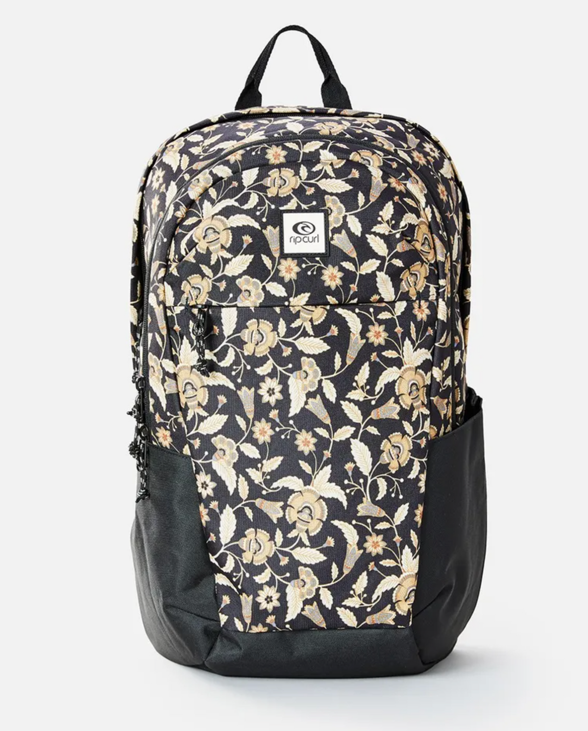 The Rip Curl Overtime 30L Backpack showcases a floral design with beige and light brown flowers on black. Made from recycled polyester, it includes side pockets, a front logo patch, and can hold a 15" laptop, offering everyday convenience.