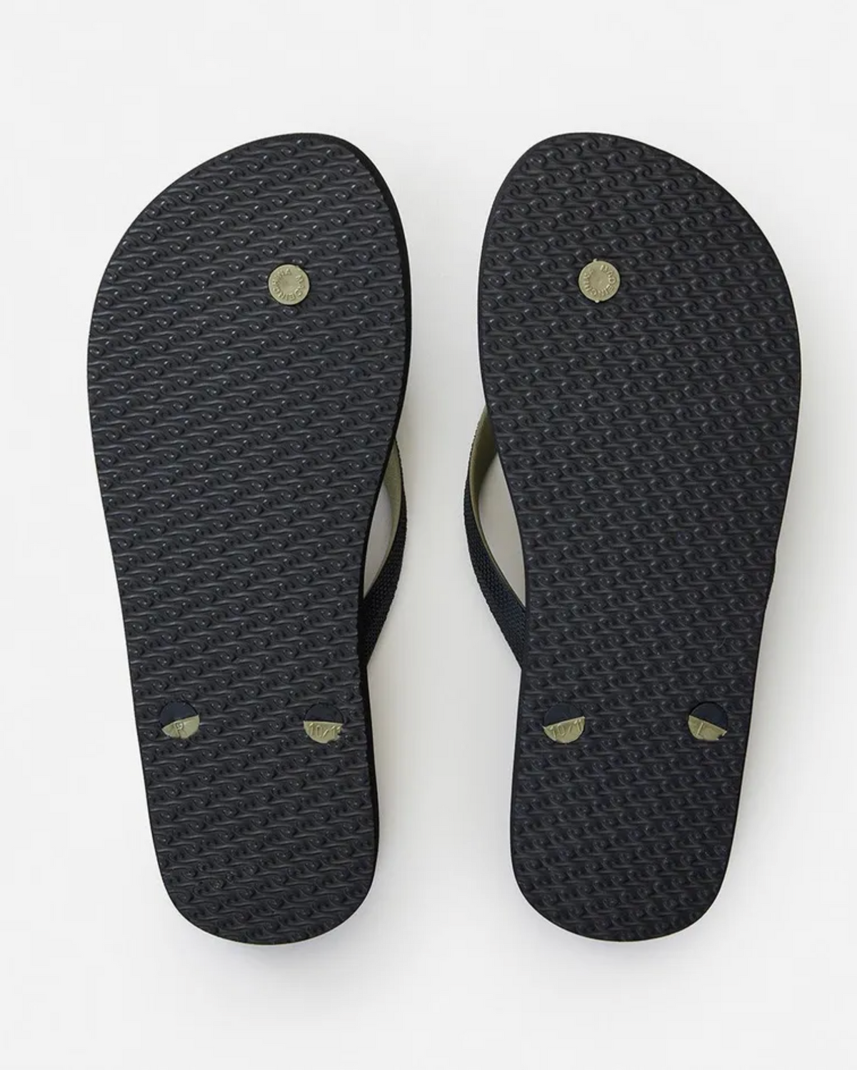 The image shows two black Rip Curl Camouflage Thongs with textured EVA rubber footbeds, circular markings, and upward straps. These flip-flops offer style and comfort for any adventure.