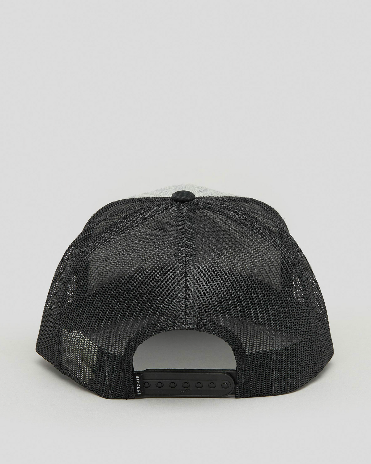 The Rip Curl Routine Trucker cap, featuring a black mesh design with an adjustable plastic snap strap and an iconic white front panel partially visible, is displayed from the back against a light gray background.