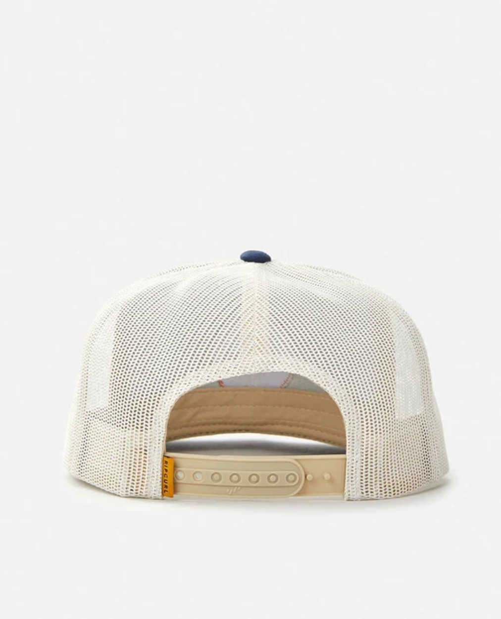 A back view of the Rip Curl Routine Trucker cap shows a beige brim and snapback closure. It features a white mesh body with a navy button on top, and the label inside is partially visible through the mesh.