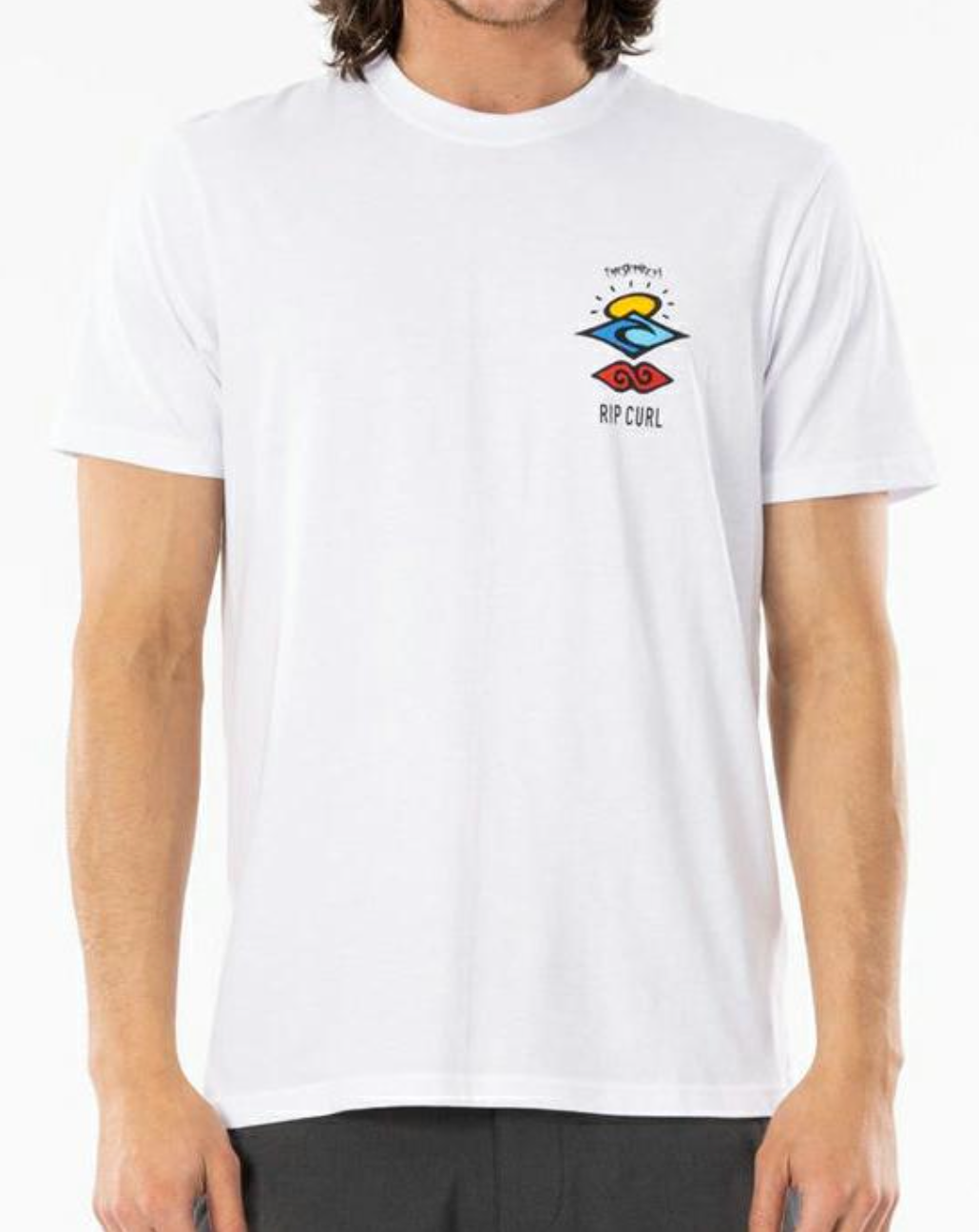 A person wearing a white Rip Curl Search Icon Tee with a colorful logo on the chest stands against a plain background. Made from organic cotton, it features a crew neck and short sleeves. They are visible from the waist up, paired with dark pants.