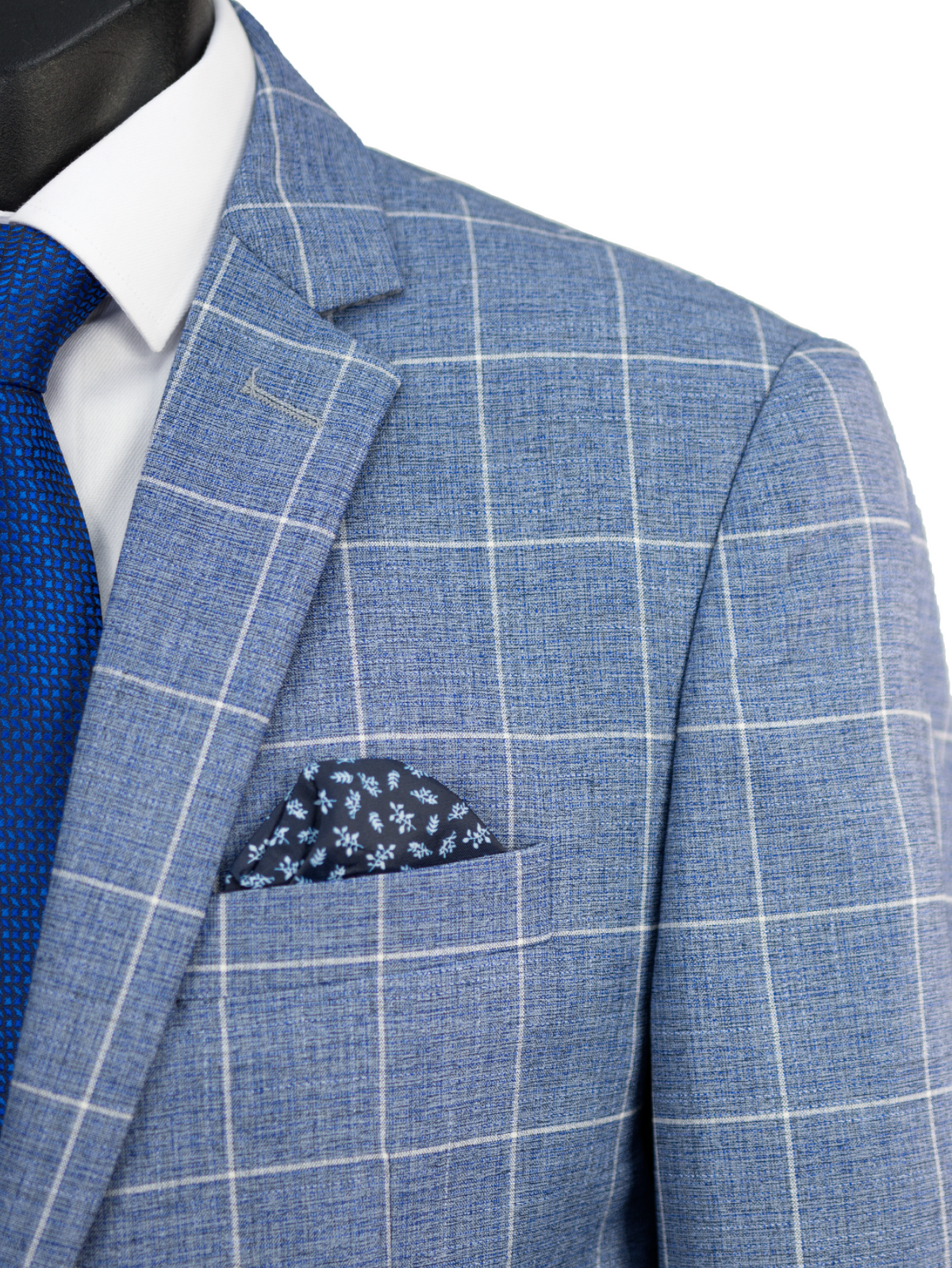 Close-up of the Scuzzatti Check Suit, featuring a slim fit blue checkered wool blend jacket paired with a white shirt and textured blue tie. A dark blue pocket square with a floral pattern is elegantly placed in the jacket's pocket.
