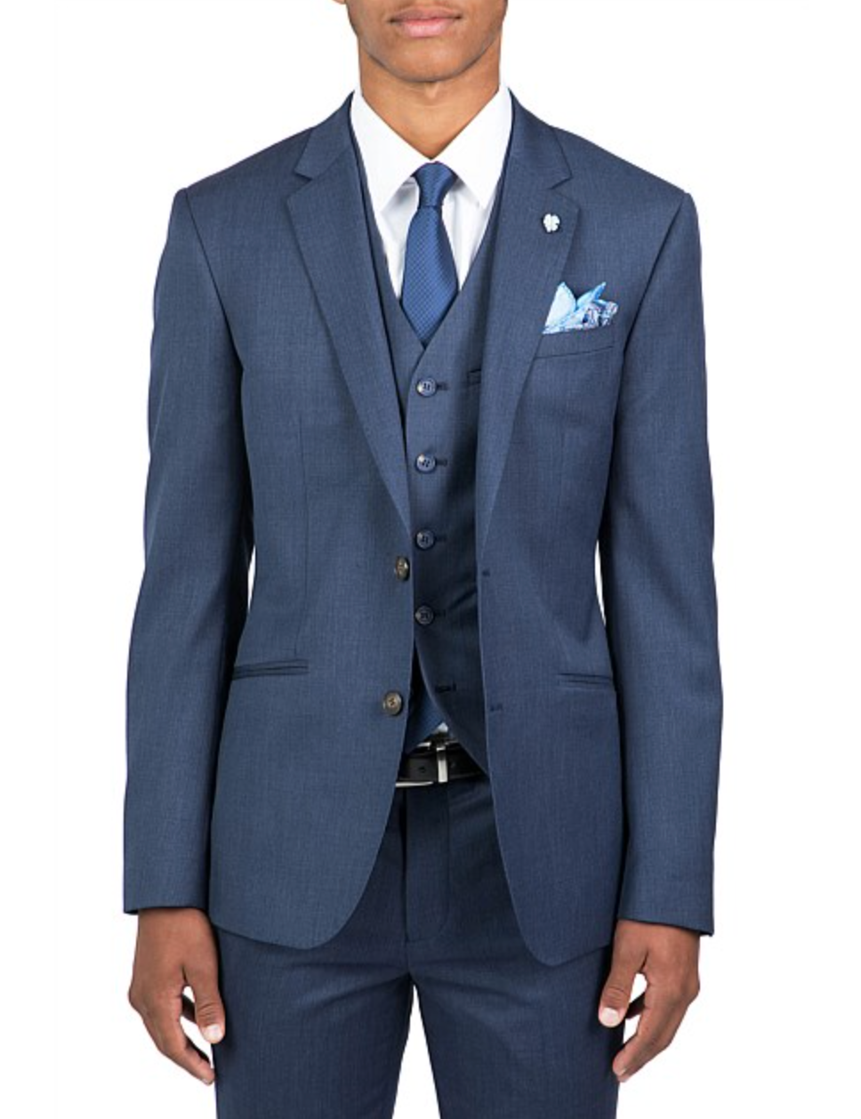 Someone is dressed in a tailored blue Uberstone Troy Jacket three-piece suit with a slim fit, shirt, and tie. The outfit includes a matching pocket square and small lapel pin on the jacket's notch lapel, all set against a plain white background.