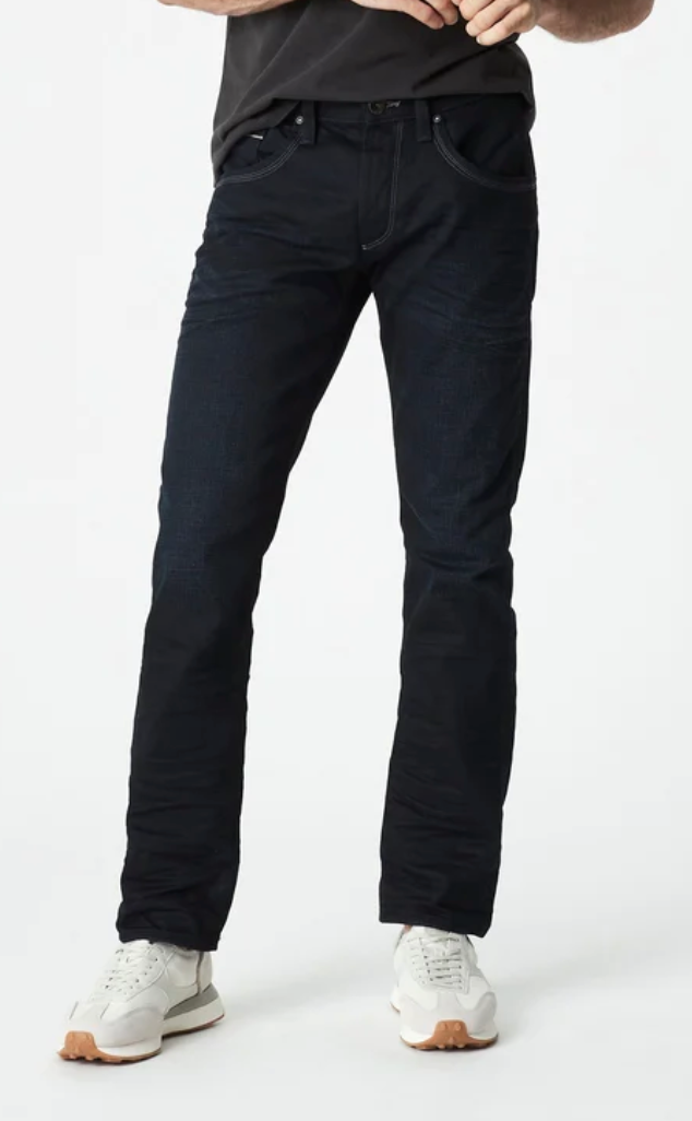 Wearing Mavi Marcus Slim Straight Jeans, a black shirt, and white sneakers, a person stands against a plain white background with only the lower half of their body visible.