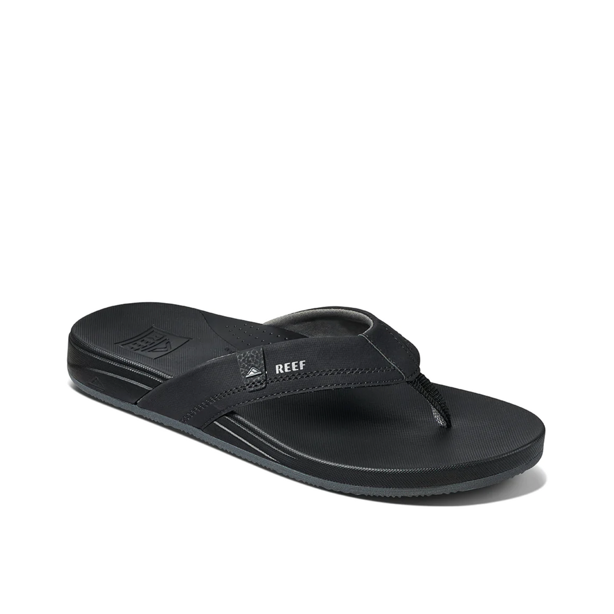 The REEF Cushion Spring is a black flip-flop with a textured sole and straps, providing comfort with arch support. It features the "REEF" brand on the strap and offers a sleek synthetic leather design, ideal for casual wear.
