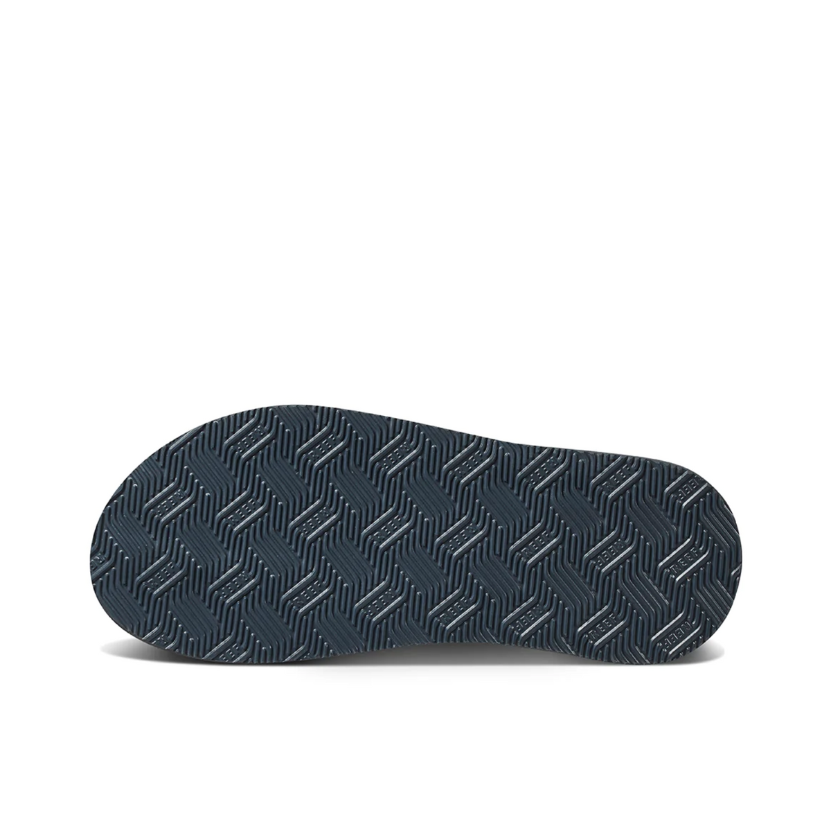 A close-up of the REEF Cushion Spring shoe sole, showcasing a dark hue with a geometric tread pattern—zigzag and rectangular shapes for grip—and a durable rubber sponge outsole.