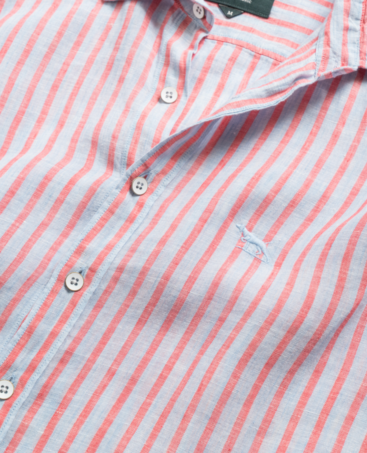A close-up of the Rodd & Gunn Mclean Park Oxford Sports Fit Shirt, featuring vertical pink and white stripes, white buttons, sports fit, and a small embroidered blue whale logo on the chest.