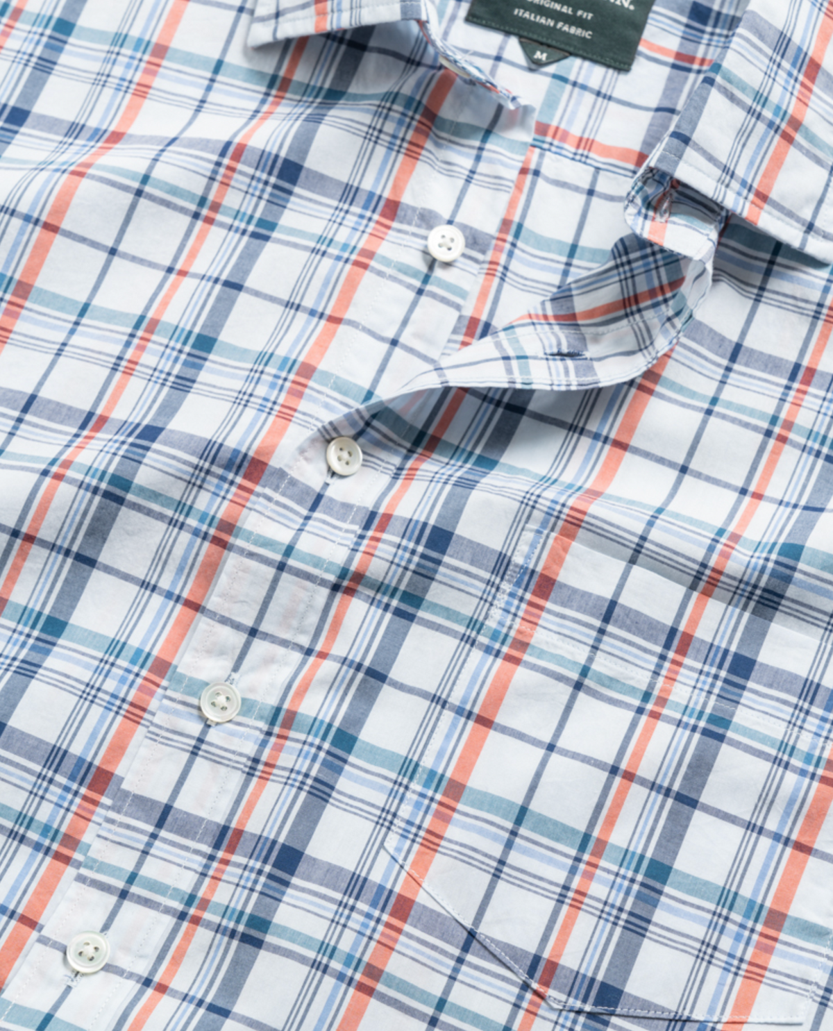Close-up of a Rodd & Gunn Rodeo Drive Shirt featuring a plaid pattern in blue, red, and white. Made from 100% cotton, this original fit, lightweight shirt showcases a visible collar, buttons, and pocket seam.