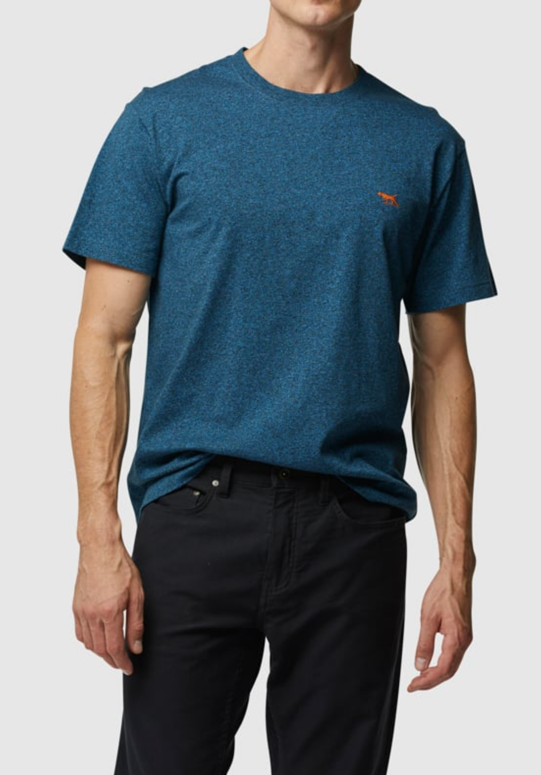 A person in a Rodd & Gunn The Gunn T-Shirt, blue speckle sports fit crafted from Australian Cotton, with a small orange chest logo and black pants stands against a plain background. The face is not visible.