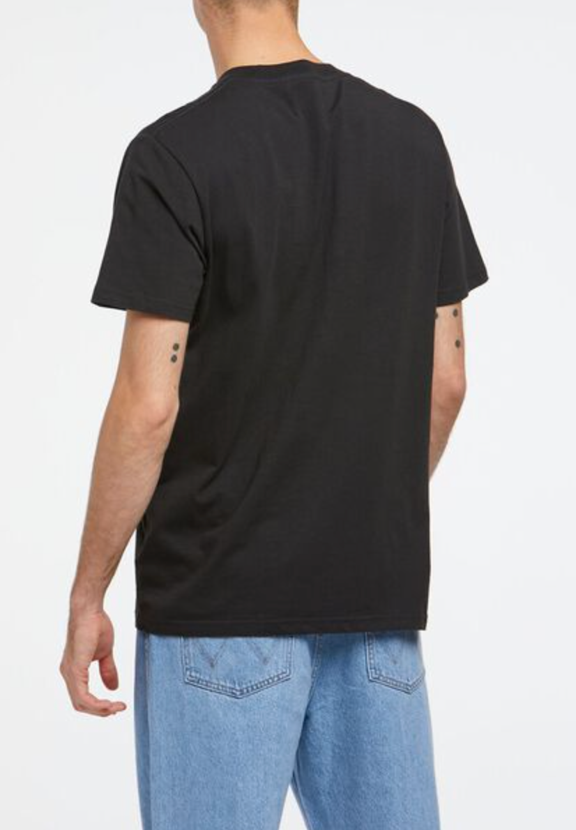 A person wearing a Wrangler Classic Logo Tee in black and light blue jeans is shown from the back on a white background. The loose-fit casual tee is made from 100% cotton, and the jeans feature visible pocket stitching. They have short hair and small arm tattoos.