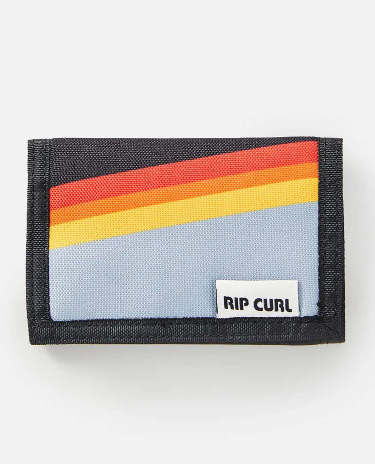 The Rip Curl Surf Revival Surf Wallet has a vintage design with diagonal red, orange, and yellow stripes on light blue. Made of recycled polyester, it features a black border and a white patch with the "RIP CURL" logo in bold black letters.