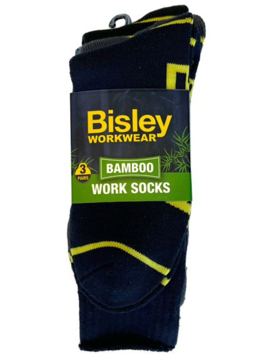 The Bisley Bamboo Work Sock 3pk includes three pairs made from breathable, moisture-wicking material. The dark socks feature yellow accents and come in a package with a dark blue and green design adorned with bamboo illustrations.